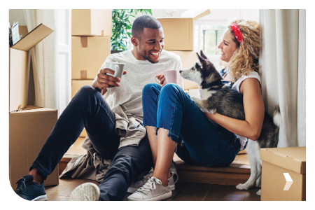 Happy Couple playing with dog while sitting in doorway at new house